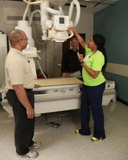 Radiology technologist Kendra Christian explains a table brake issue to technicians Vince Partman and Wally Davis.